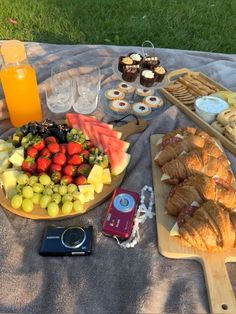 a table topped with lots of food and drinks on top of a blanket next to a cell phone