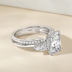 This exquisite fat oblong cut sterling silver three stone engagement ring set is a testament to timeless elegance and romance. The main ring's center stone, a stunning fat oblong cut gemstone. The opening of the secondary ring features two delicate and bright pear-shaped cut stones, creating a captivating display of brilliance. The stones are expertly set to catch the light from every angle, creating a sparkling effect that is truly breathtaking. It's a timeless three stone ring set that will be Three Stone Ring Settings, Three Stone Engagement, Three Stone Engagement Rings, Three Stone Rings, Three Stone, Bridal Sets, Engagement Ring Settings, Diamond White, Ring Sets