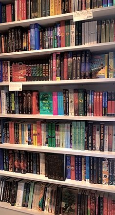 a book shelf filled with lots of different colored books on top of white shelving