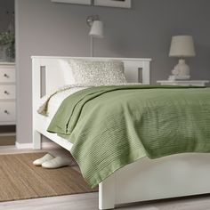 a white bed with green bedspread and pillows