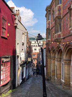 an old fashioned street light in the middle of a narrow alleyway between two buildings