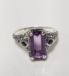 "Thanks for shopping our vintage estate store. We tend to sell well below wholesale and truly hope you enjoy all of our items. Many of the items are one of a kind, so please enjoy scrolling through the pictures and hopefully something will catch your eye. Estate sterling silver 925 natural 1ct amethyst emerald cut .15ct sapphire filigree ring. Beautiful ring, one that was custom made in our shop, meaning we set the gems into the setting. Ring size: 6 or 7 please select Setting: 1/2\" by 3/8\" 9mm Band width: 1.5mm Weight: 3.10 grams Beautiful ring one that you will love. Gems testing natural, but maybe created." Vintage Emerald Cut Amethyst Ring For Anniversary, Classic Amethyst Ring With Vs Clarity As A Gift, Vintage Amethyst Ring With Accent Stones For Anniversary, Classic Amethyst Gift Ring, Classic Silver Amethyst Ring For Anniversary, Antique Amethyst Ring Stamped 925 For Anniversary, Classic Sterling Silver Amethyst Ring For Anniversary, Classic Sterling Silver Amethyst Ring With Emerald Cut, Vintage Emerald Cut Amethyst Ring Gift