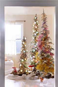 two christmas trees are decorated with lights and snow