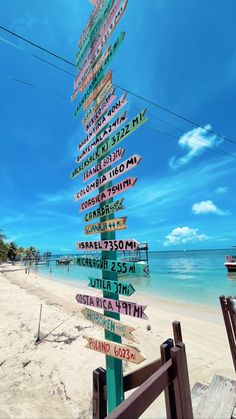 a wooden sign post on the beach with many signs pointing in different directions to various destinations