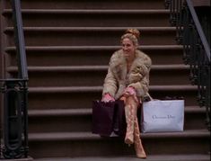 a woman is sitting on the steps with shopping bags