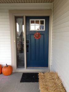 a blue front door with hay bales and pumpkins