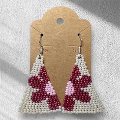 a pair of red and white beaded earrings hanging from a hanger on a wall