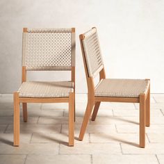 two wooden chairs sitting side by side on a tile floor in front of a white wall