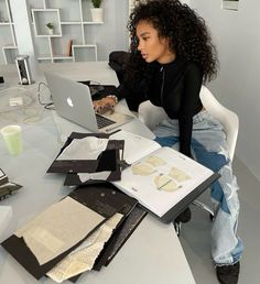 a woman sitting at a table with a laptop and papers in front of her,