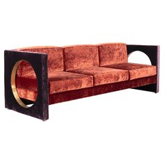 an orange couch with a black frame and gold accents on the armrests, sitting in front of a white background