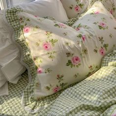 a bed with white sheets and pink flowers on it, next to a window sill