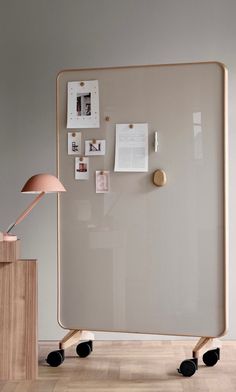 an office with a large white board on wheels and a pink lamp next to it