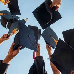 several people in graduation caps and gowns are throwing their hats into the air together