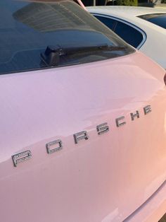 a pink car parked next to other cars in a parking lot with the word porsche written on it