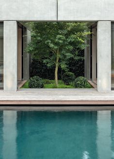 an empty swimming pool in front of a concrete structure with trees and bushes on either side