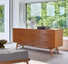 a living room scene with focus on the dresser and large window in the back ground