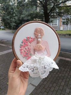 a person is holding up a cross stitched picture