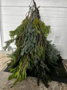 a pile of evergreen branches sitting on top of a black mat in front of a white door