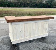 a large wooden box sitting on top of a parking lot next to a grass covered field