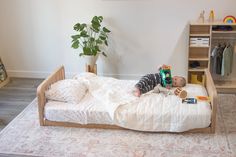 A montessori floor bed with two headboards and a little boy laying on top Baby Floor Bed, Low Floor Bed, Wooden Toddler Bed, Room Sharing, Modular Bed, Low Profile Bed Frame, Kid's Bed, Montessori Floor Bed, Toddler Floor Bed