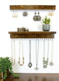 a wooden shelf filled with lots of necklaces next to a potted green plant