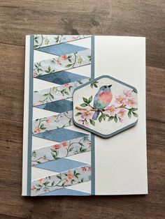 a close up of a card on a wooden surface with flowers and birds in the background