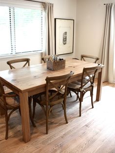 a dining room table with four chairs and a basket on top of it in front of a window