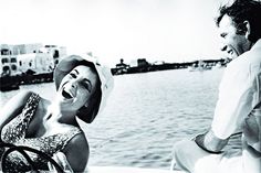 a woman in a bathing suit sitting on a boat with a man looking at her