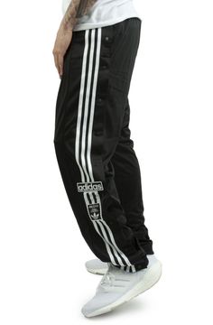 ADIDAS Black sport pants for men. Originally created for warming up on the pitch, the adidas adibreak pants have become a symbol of freedom of expression. Unbutton them at the ankles, up to the knees, or keep all the buttons closed, you decide how to wear them. The model wears a size L and is 187cm tall. Medium temperature washing and ironing is recommended. Autumn winter season. ATHLETES WORE THEM FIRST. NOW IT'S YOUR TURN. ORIGINALLY MADE FOR WARMING UP ON THE PITCH, THE ADIDAS ADIBREAK TRACK Relaxed Fit Sportswear Bottoms With Three Stripes, Adidas Athleisure Pants With Logo, Adidas Relaxed Fit Sports Bottoms, Adidas Relaxed Fit Sport Bottoms, Adidas Relaxed Fit Jogging Bottoms, Adidas Relaxed Fit Pants With Logo, Adidas Relaxed Fit Pants With Three Stripes, Adidas Athleisure Bottoms With Three Stripes, Adidas Relaxed Fit Moisture-wicking Bottoms