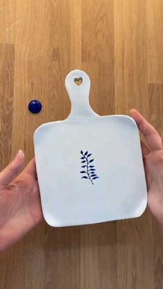 two hands holding a white serving dish with a blue design on the front and side