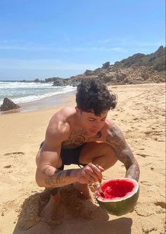 a man is sitting on the beach with a watermelon