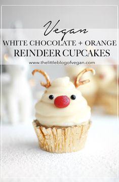 a cupcake with white chocolate and orange reindeer decorations on top, in front of other cupcakes