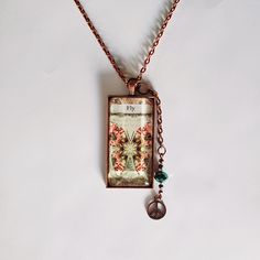 a necklace with a butterfly and flowers on it