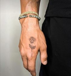 a man with a rose tattoo on his hand and wrist is holding onto a bracelet