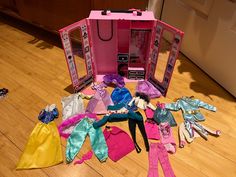 there is a barbie doll house with clothes all over the floor and in front of it