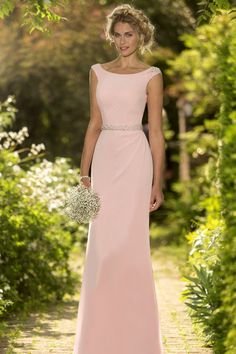 a woman in a long pink dress standing on a path