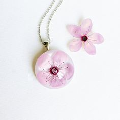 This cherry flower necklace is made from a real cherry flower picked up from the place where I live. A unique sakura necklace as the most unique birthday gift idea for women. In general, a cherry flower necklace (japanese flower necklace) is an outstanding full of significance complement for you. This sakura blossom necklace is part of my pale pink jewelry. The hypoallergenic stainless steel and the high-gloss crystalline resin gives this cherry flower necklace a precious and enamelled look. Use Dainty Pink Pendant Flower Necklace, Gift Flower Pendant Necklace With Flower Decoration, Delicate Round Pink Necklace, Pink Round Necklace For Mom, Blossom Petal Shaped Jewelry For Gifts, Blossom Colored Flower Pendant Jewelry Gift, Blossom Flower Pendant Jewelry Gift, Blossom Color Flower Pendant Jewelry For Gift, Blossom Color Flower Pendant Jewelry As Gift