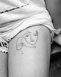 a woman's thigh with a small tattoo on her left leg and the outline of a face