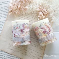 two candles are sitting on top of a piece of paper with flowers in the background