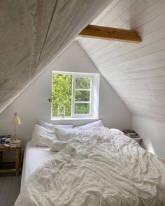 an unmade bed sitting under a window in a bedroom