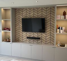 a flat screen tv mounted to the side of a wall in a living room next to bookshelves