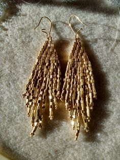 I purchased these lovely triangle seed beads with the idea these earrings would be a great idea. I love the results.  These swinging, glistening, dangling confections hang on kidney ear wires.  A great gift for someone special or just for you.  Choose matte gold or galvanized gold. 3.5" total length Gold Teardrop Earrings With Tiny Beads, Gold Dangle Earrings With Tiny Beads, Triangle Beaded Earrings For Gifts, Beaded Triangle Earrings For Gifts, Elegant Triangle Beaded Earrings Gift, Elegant Triangle Beaded Earrings For Gift, Elegant Triangular Beaded Earrings For Gift, Seed Beaded Earrings, Earrings Golden