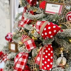 a christmas tree decorated with red and white bows, ornaments and tags on it's branches