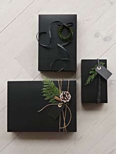 two black boxes with christmas decorations on them, one is wrapped in twine and the other has a pine cone