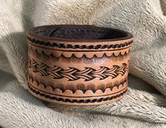 a brown leather cuff with black stitching on it and a white blanket in the background