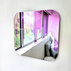 there is a mirror on the wall that has pink and purple decorations in it,