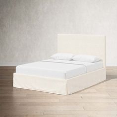 a white bed sitting on top of a hard wood floor