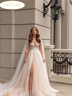 a woman standing in front of a building wearing a white wedding dress with high slit