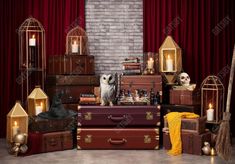 an owl sitting on top of several suitcases in front of a brick wall with candles