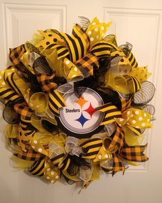 a yellow, black and white wreath with the pittsburgh football logo on it hanging on a door